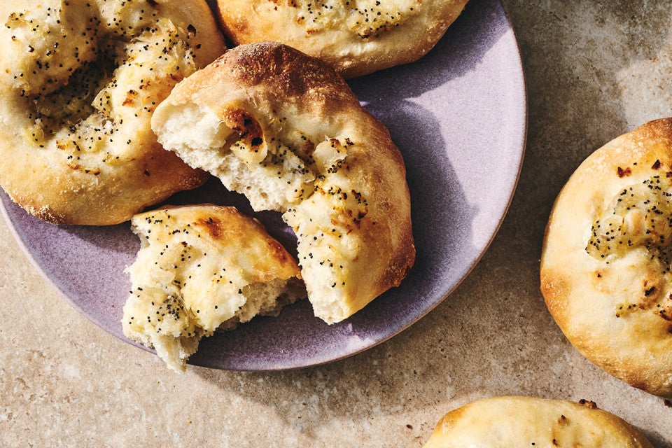 Classic Bialys on a plate with one broken apart to show the chewy interior.