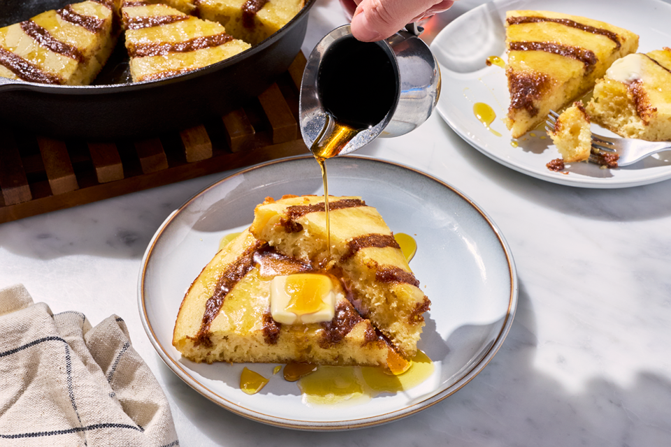 Pouring maple syrup onto a Cinnamon Roll Skillet Pancake.