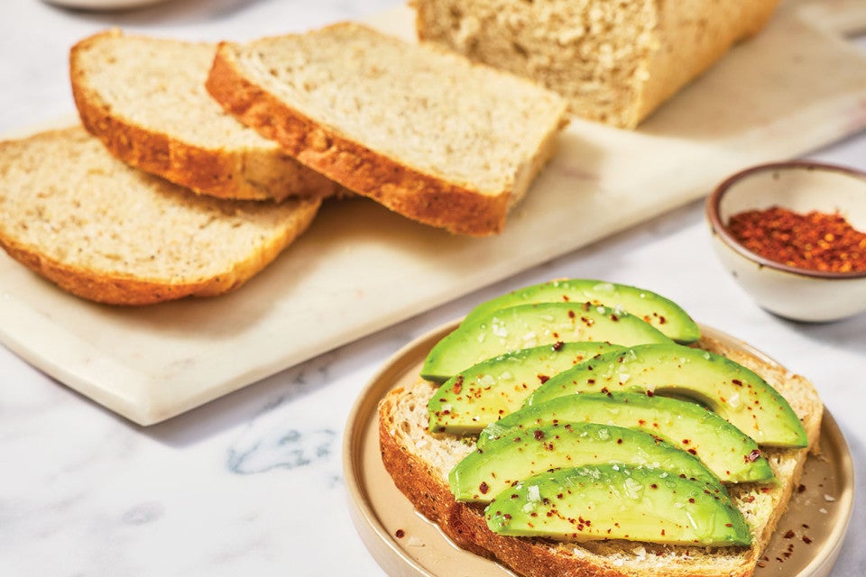 Avocado toast in front of sliced Clay's Multigrain Sourdough bread.