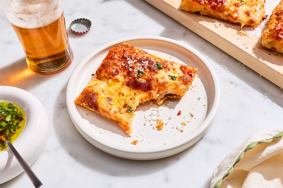A slice of Flaky Puff Crust Pizza on a plate with a bite taken out of it