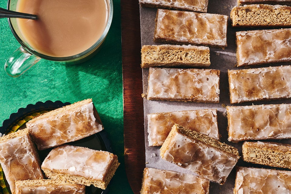 Lebkuchen on a sheet tray in half the photo and on the left side, lebkuchen is on a plate and there's a beverage in the corner.