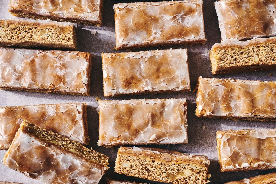 Lebkuchen Bars on a sheet tray arranged imperfectly and showing the gingerbread interior and glazed top.