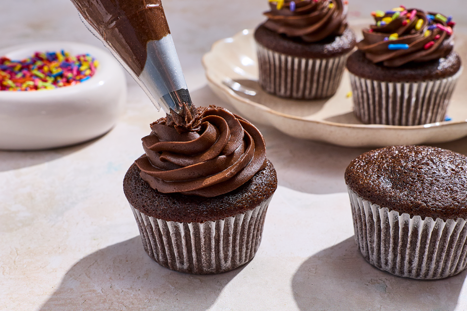 Piping frosting onto a Small-Batch Chocolate Cupcake.