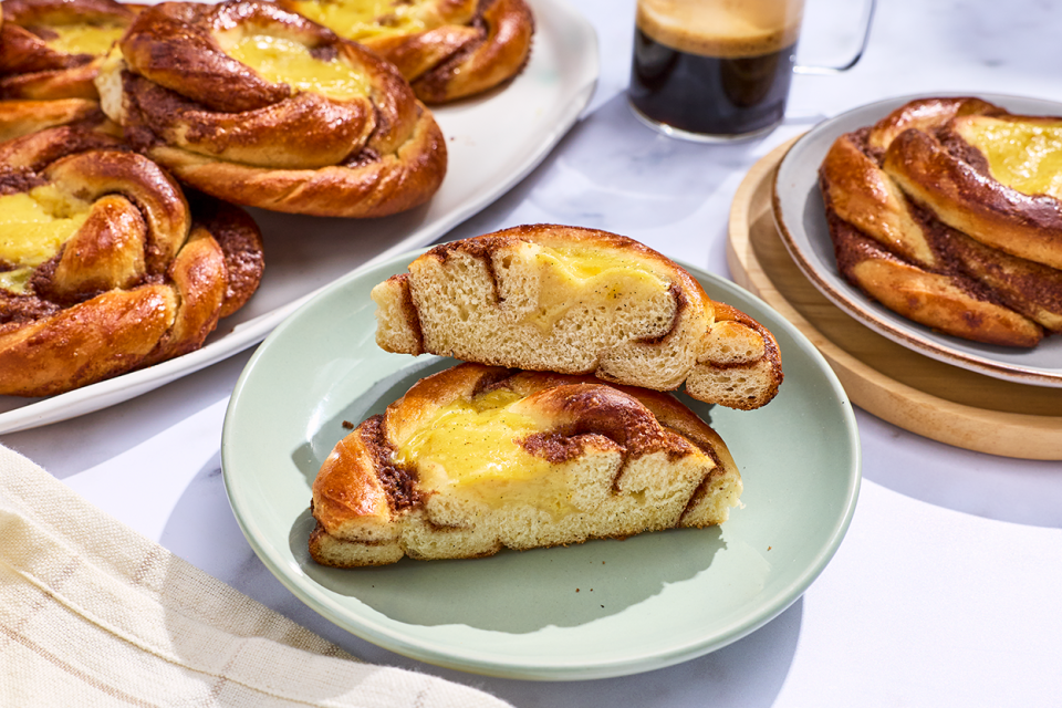 A sunshine bun sliced in half on a plate and others arranged in the background.