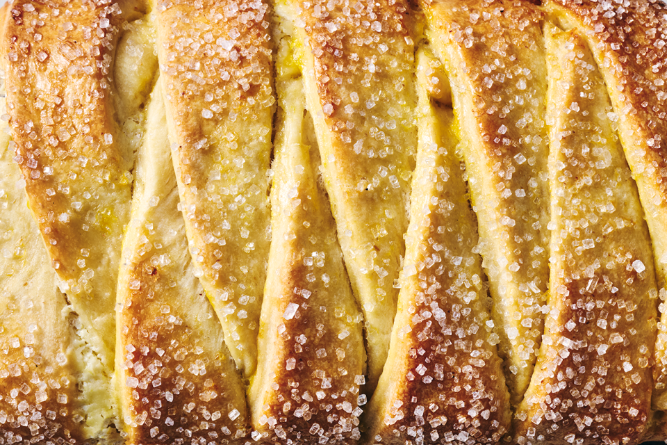 Detailed photo of Cheese Filled Sweet Braid seen from above showing sparkling sugar and a overlapping layers of bread.