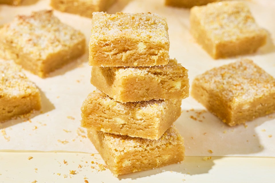 Stacked Alex Roberts Lemon Citrus Blondies on a countertop.