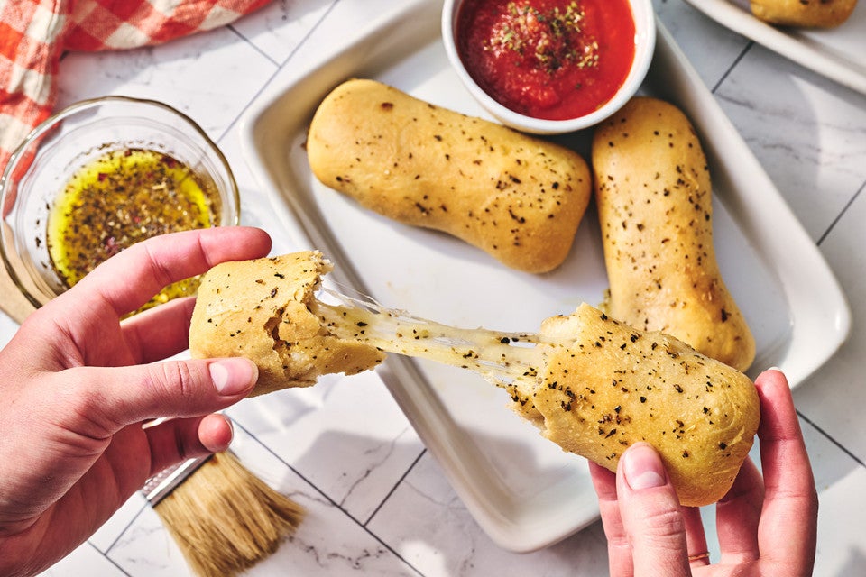 Pulling a Cheese Stuffed Breadstick apart to show the cheesy gooey center.