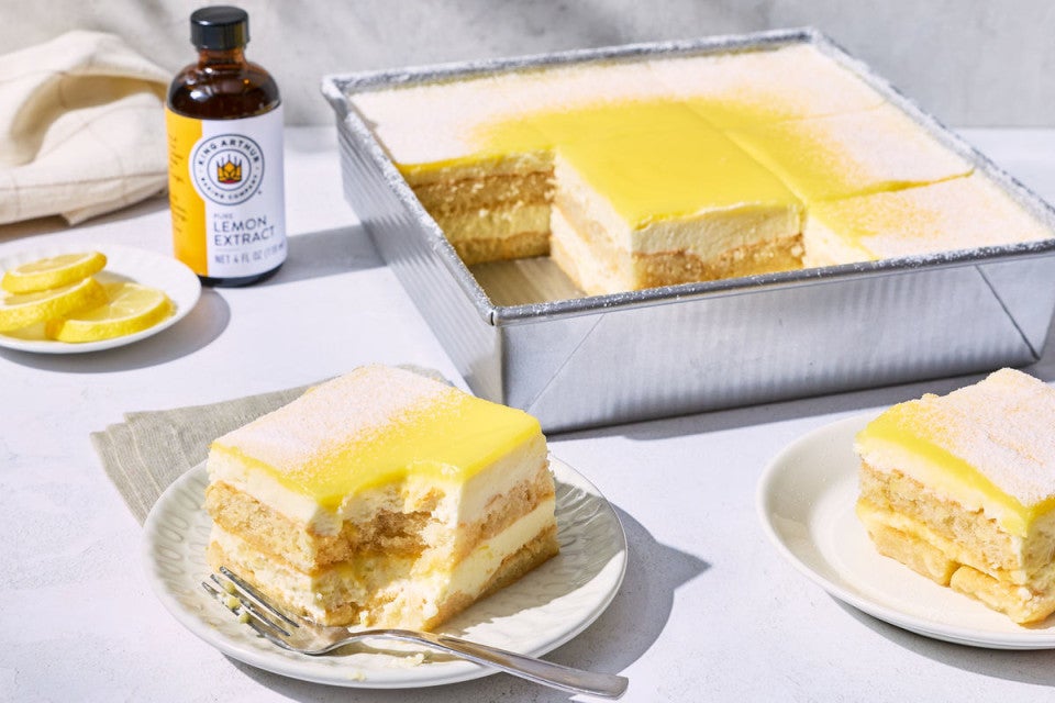 A pan of lemon tiramisu with a few slices removed and a bottle of King Arthur Pure Lemon Extract in the background