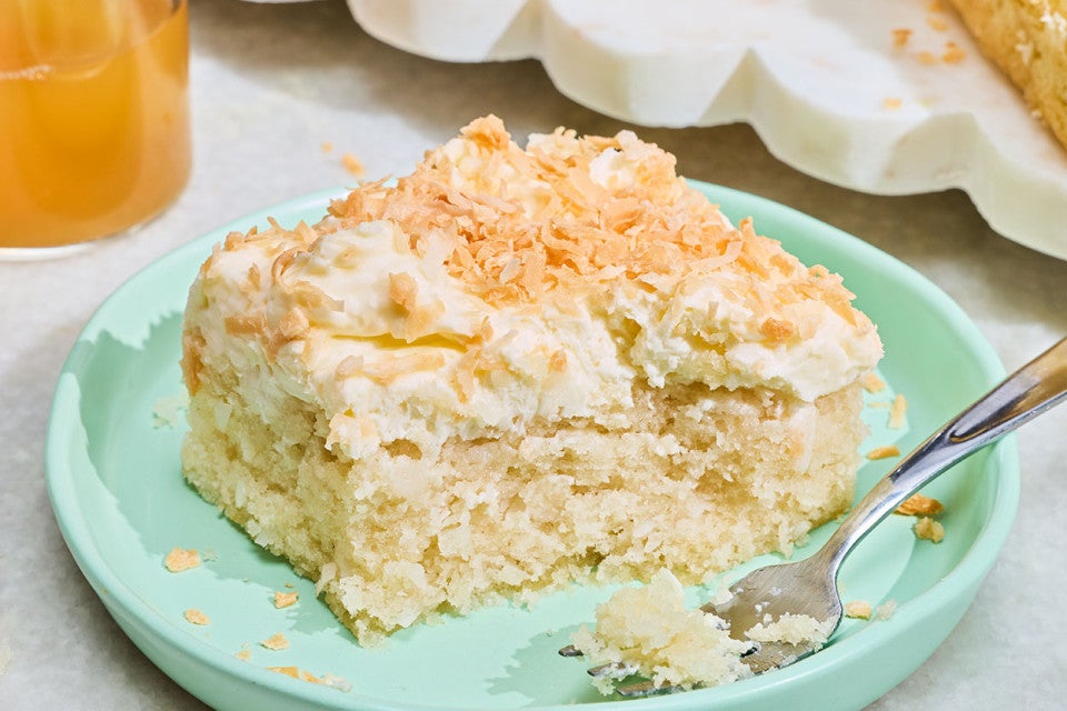 Creamy Coconut Sheet Cake on a plate with a small bite on a fork.