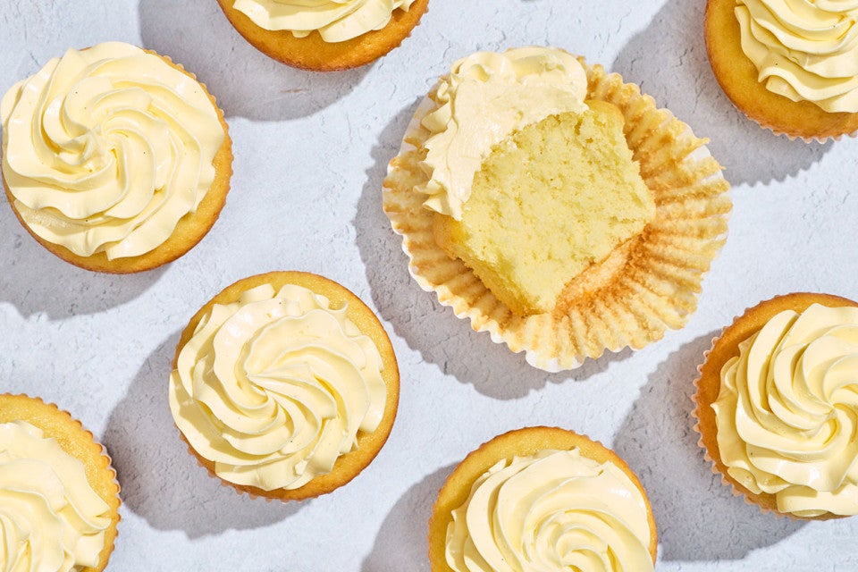 Cupcakes seen from above with French Buttercream as the frosting. One cupcake is sliced in half and laying on its side.