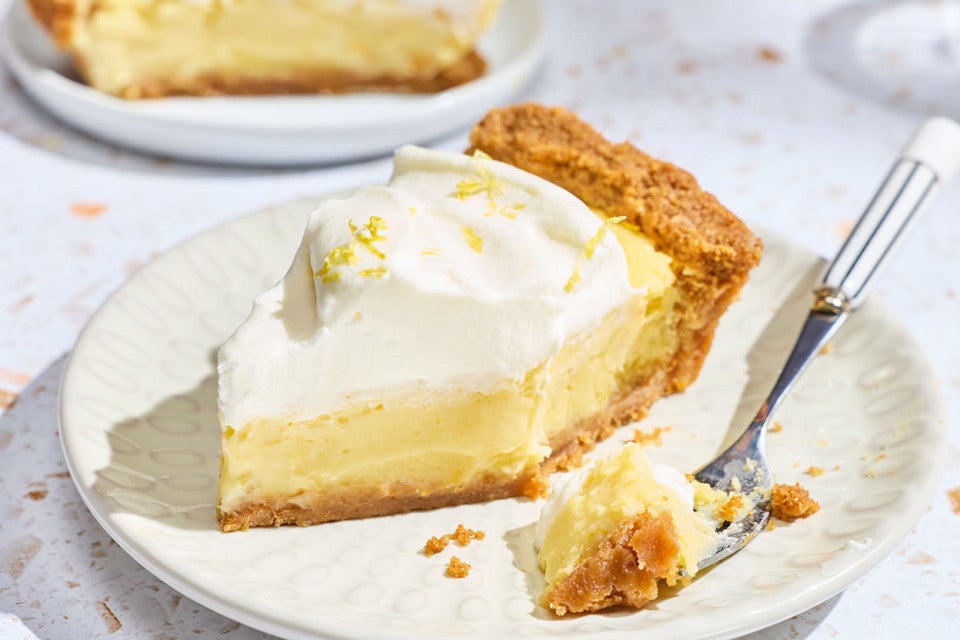 A Lemon Cream Pie slice with a bite on a fork.