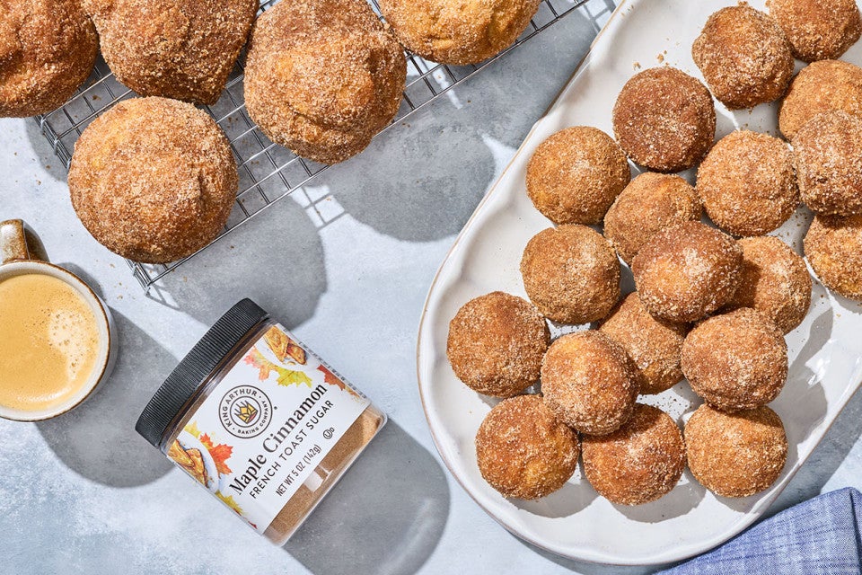 Maple French Toast Mini Muffins shown from above on a counter with a jar of King Arthur Maple Cinnamon.