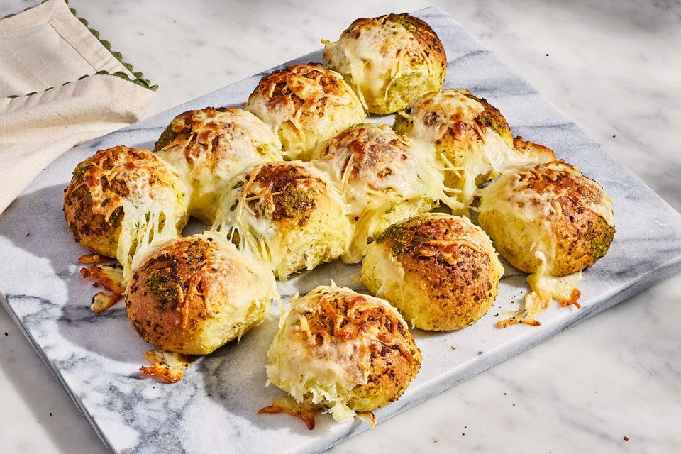 Fresh-baked Cheesy Pesto Pull-Apart Rolls shown on a marble platter
