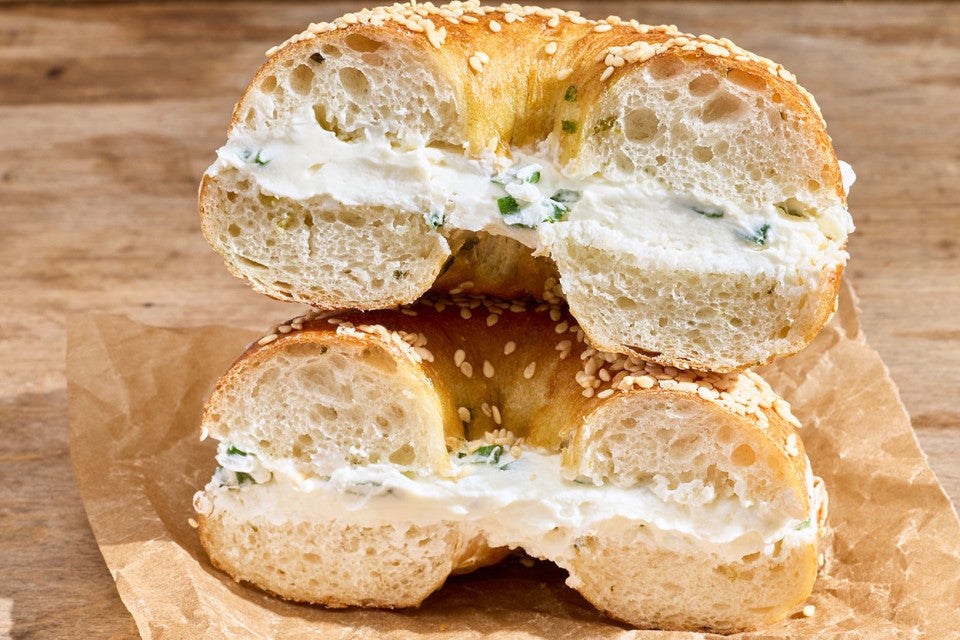 A Sesame Sourdough Discard Bagel sliced and stacked with the sliced edge facing the camera, filled with cream cheese spread.