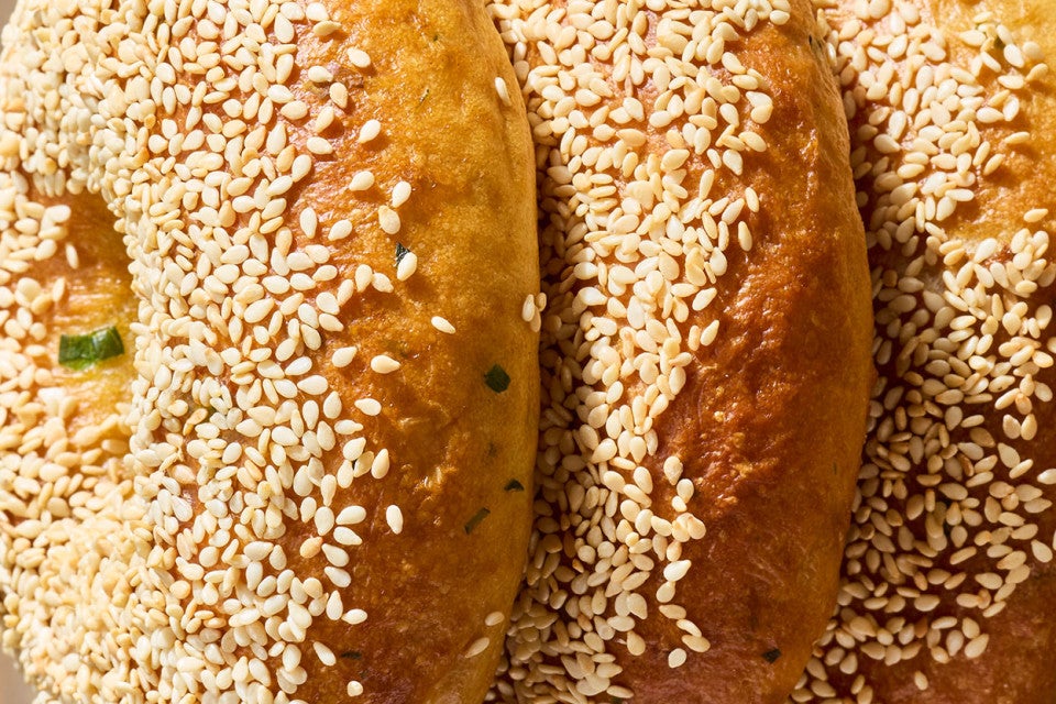Close of up three Sesame Sourdough Discard Bagels on an angle showing the sesame seeds and dark bake.