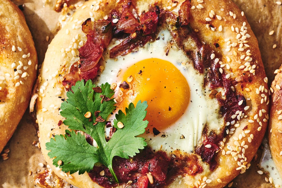 Detailed image of Breakfast Shakshuka with an egg in the middle of dough and decorated with a cilantro leaf.