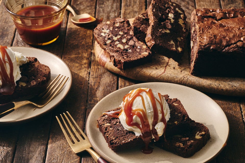 A sliced Brownie Loaf on a plate with vanilla ice cream and a caramel swirl
