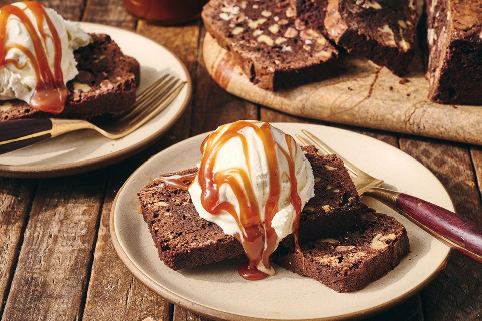 A sliced Brownie Loaf on a plate with vanilla ice cream and a caramel swirl