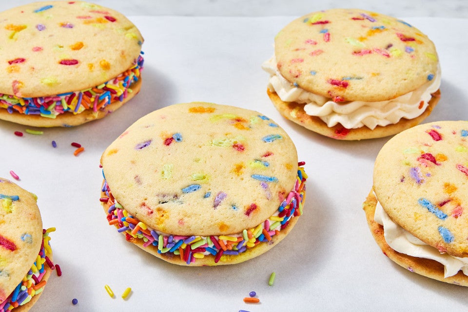Confetti Whoopie Pies on a counter with sprinkles decorating the filling around the edges.