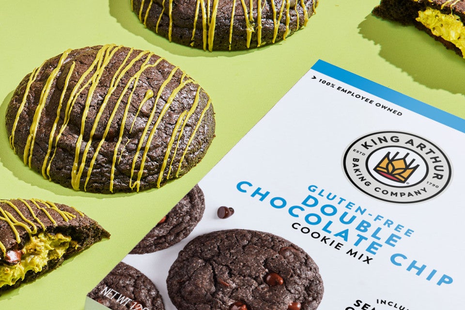 Gluten-Free Double Chocolate Pistachio Cookes on a green counter with a box of Gluten Free Double Chocolate Chip mix.