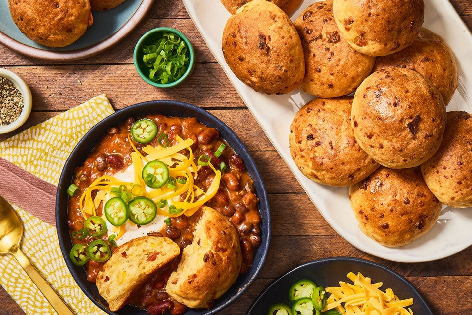 Gluten-Free Bacon Cheddar Rolls on a platter with a bowl of chili next to it. Seen from above.