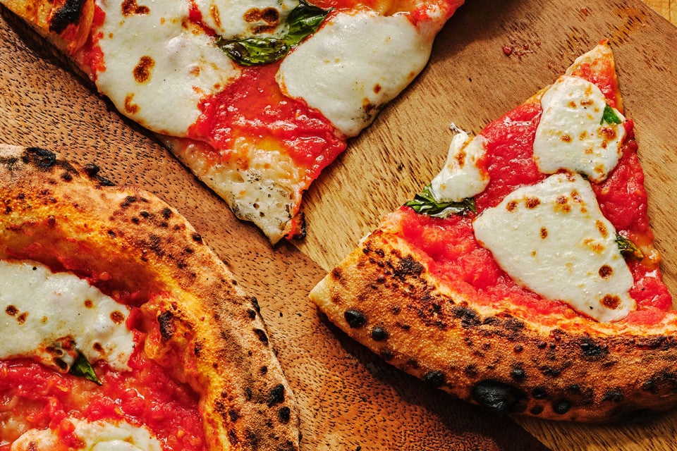 Slices of Margherita Pizza on a wooden counter.