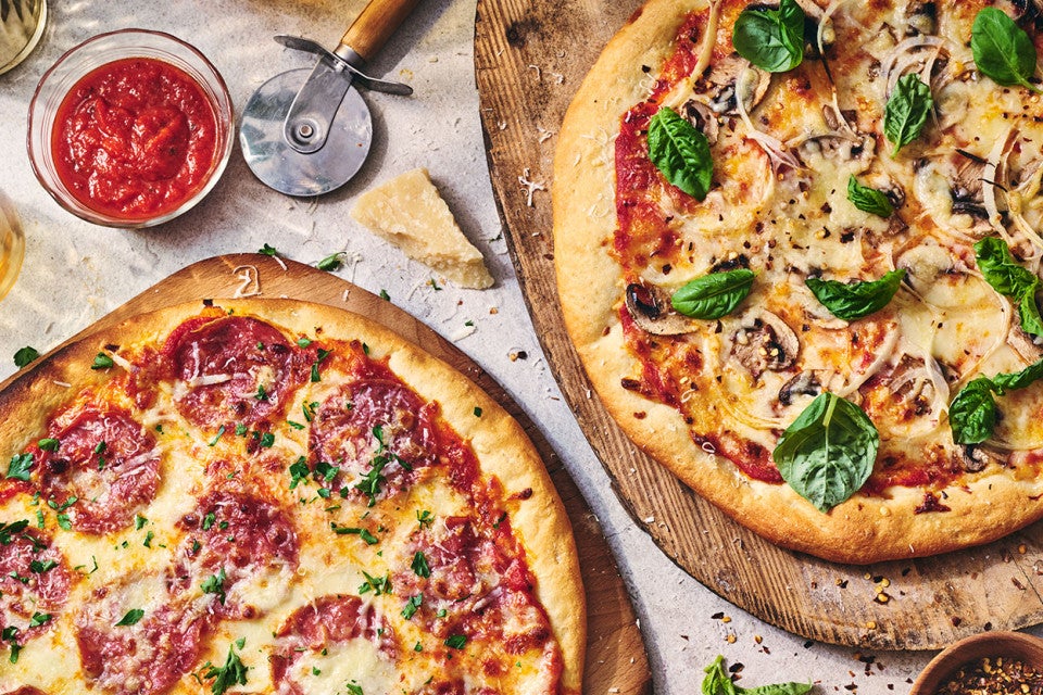Two pizzas seen from above on wooden pizza peels
