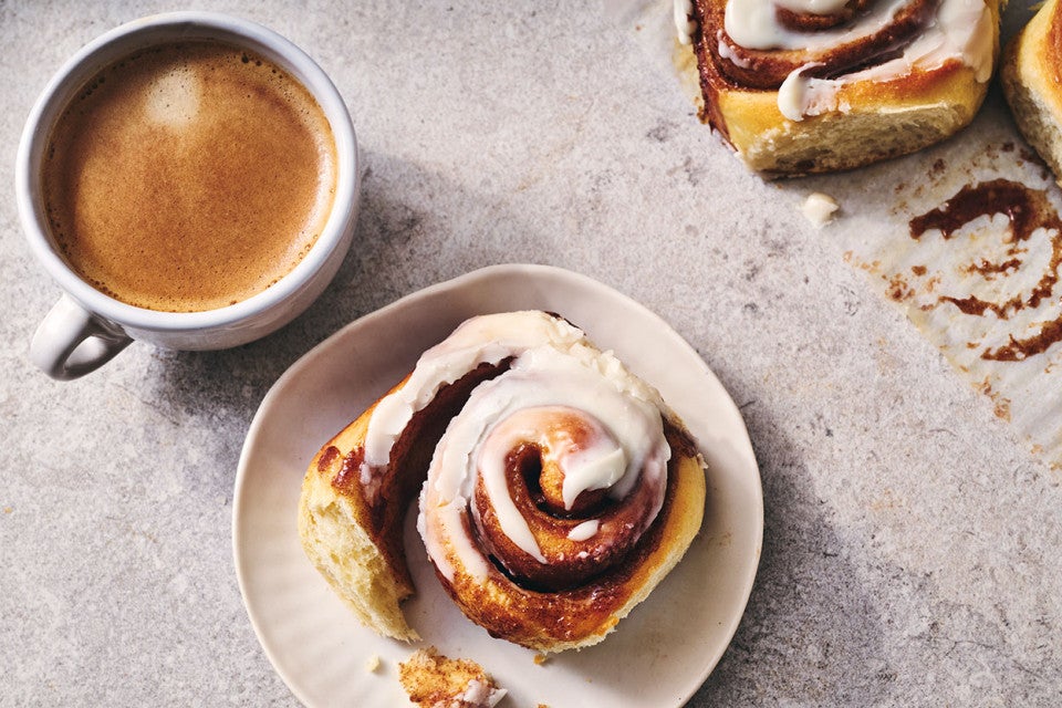 A Sourdough Cinnamon Roll on a plate accompanied by coffee - seen from above.