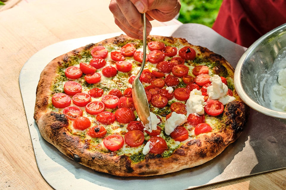 Adding fresh mozzarella to caprese style NY pizza fresh out of the oven