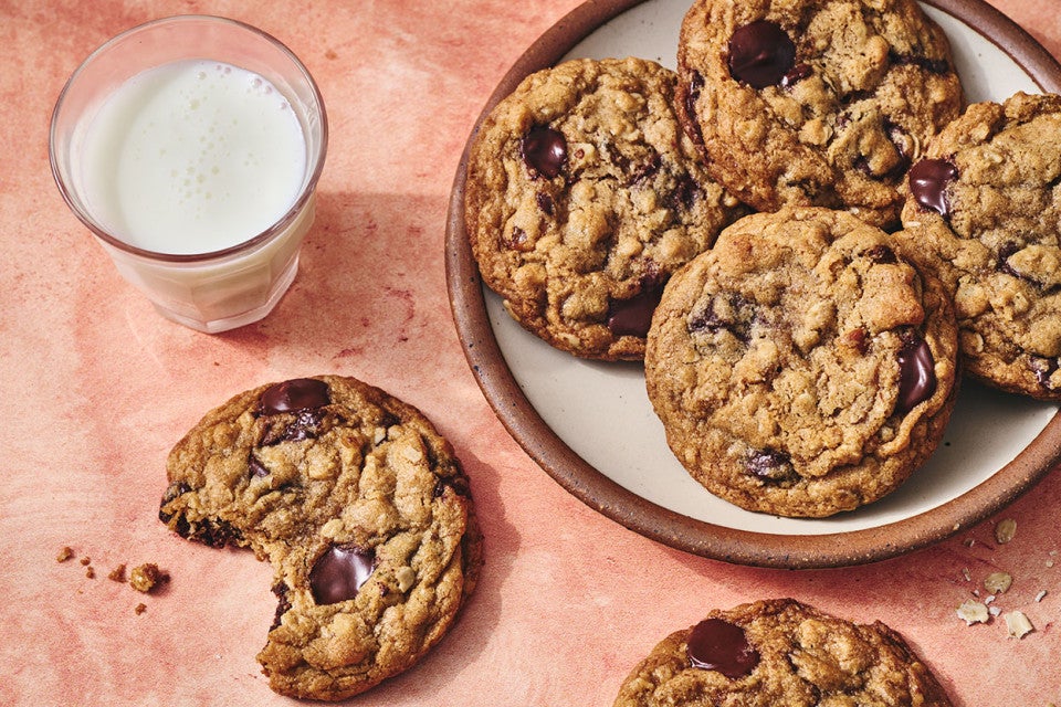 Whole Wheat Oatmeal Cookies on a plate with a glass of milk and a cookie with a bite taken out on a counter seen from above