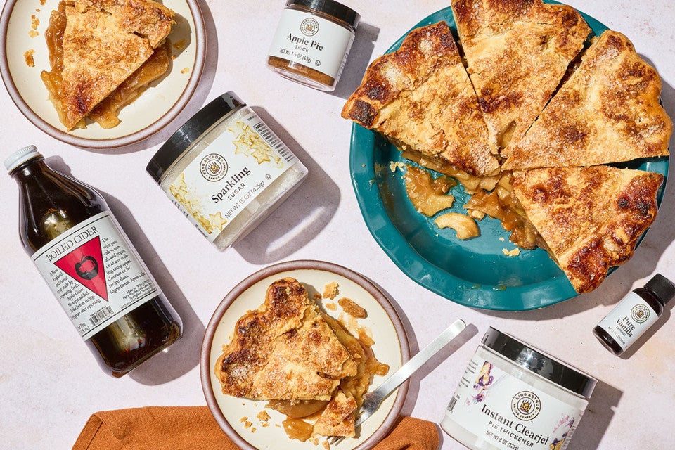 Apple pie and the ingredients to make it shown on a counter from overhead