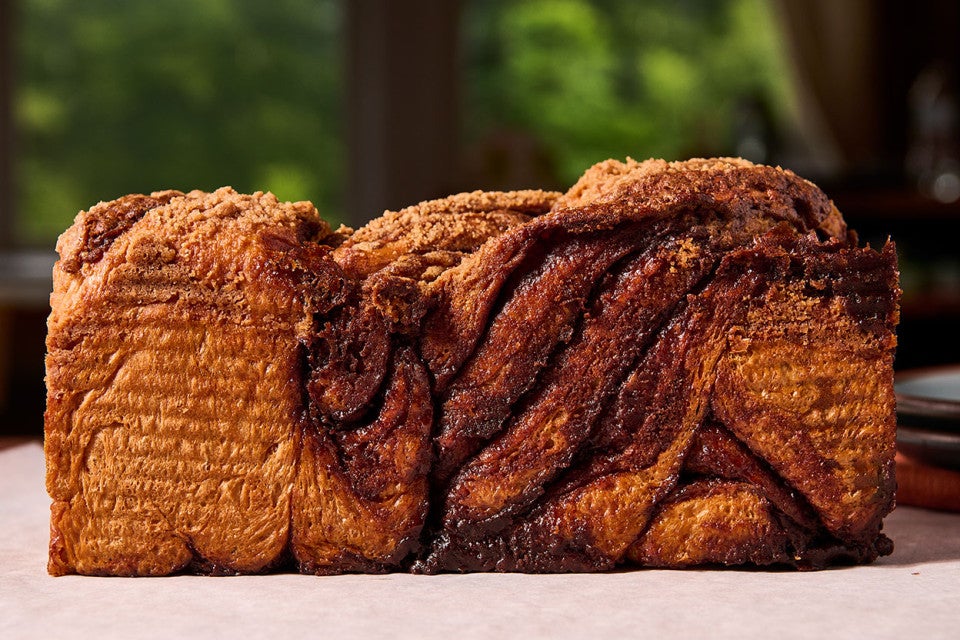 A loaf of Cinnamon Babka on a counter seen from the side with folded dough and veins of thicks cinnamon
