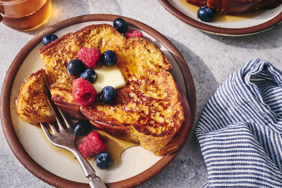 French toast on a plate with fresh berries and butter.