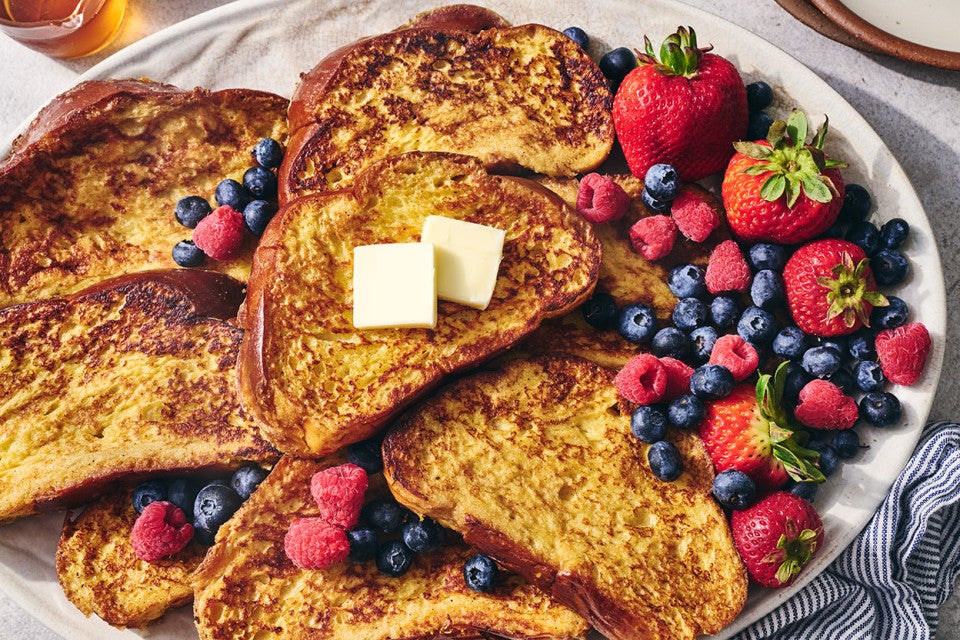 French Toast on a plate surrounded by fresh berries