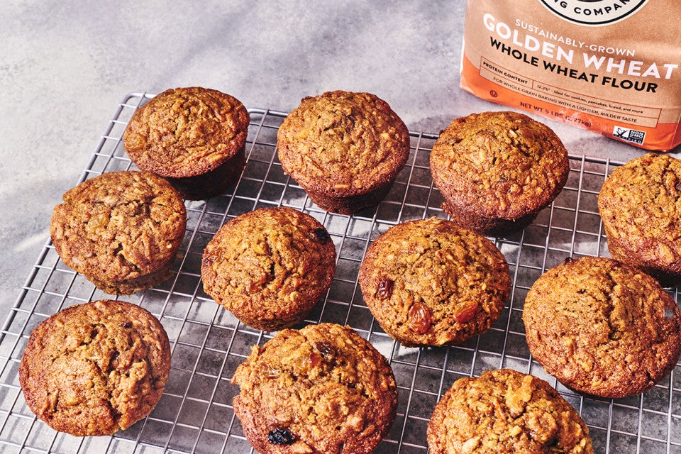 Morning Glory Muffins on a baking rack and a bag of King Arthur Baking Golden Wheat Flour in the background.