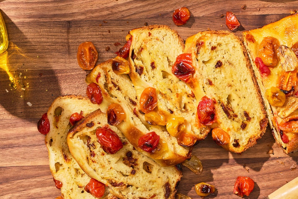 No-Knead Cheese and Tomato Garlic Bread sliced and shown on a wooden counter