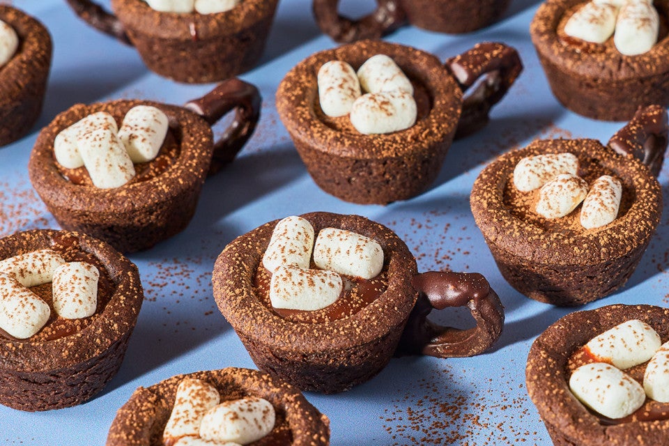 Hot Cocoa Cookie Cups arranged on a blue countertop.