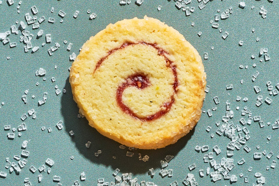 An Any-Jam Pinwheel Cookie on a counter surrounded by sparkling sugar