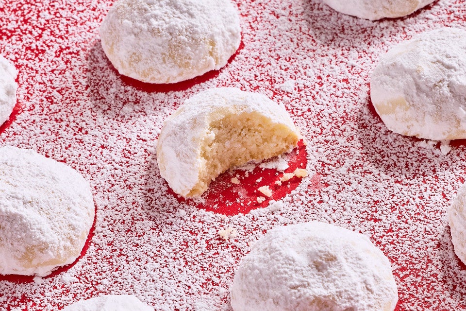 Lemon Snowball Cookies coated in powdered sugar on a red surface
