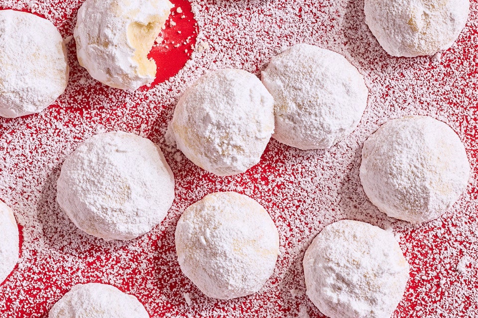 Lemon Snowball Cookies coated in powdered sugar on a red surface