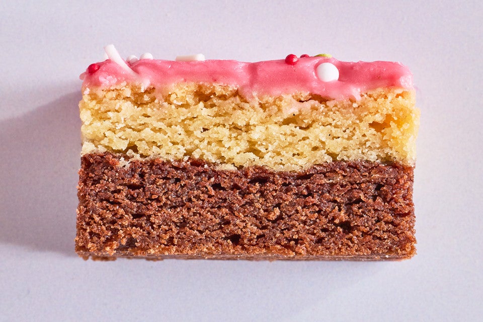 A Neapolitan Sugar Cookie Bar seen from the side showing layers of chocolate, vanilla, and strawberry