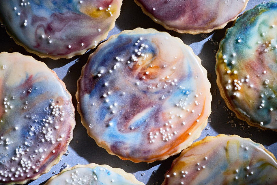 Close up of Northern Lights Iced Sugar Cookies tightly arranged on a blue background