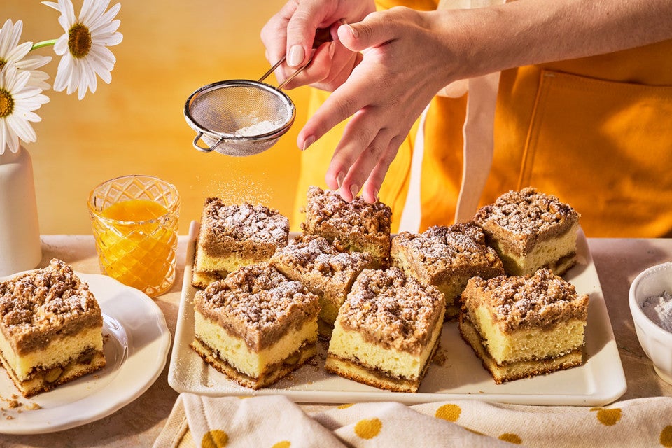 Dusting the tops of Our Favorite Sour Cream Coffee Cake with powdered sugar.