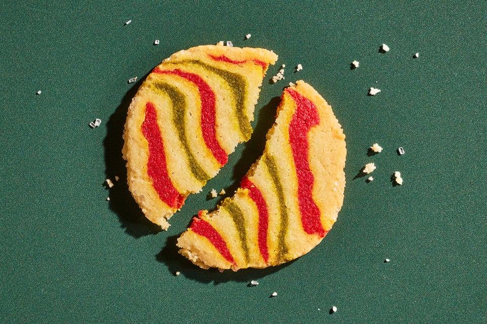 A broken Ribboned Peppermint Shortbread Cookie on a green background