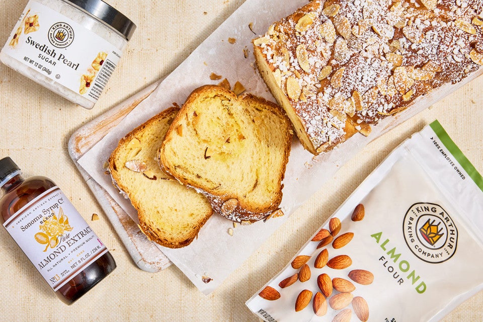 Almond Croissant Milk Bread sliced on a counter with ingredients spread around