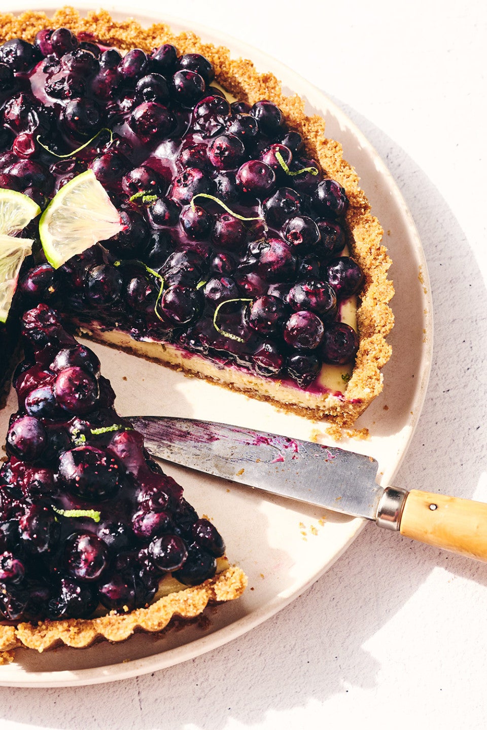 A Blueberry Key Lime Tart on a plate with a slice removed