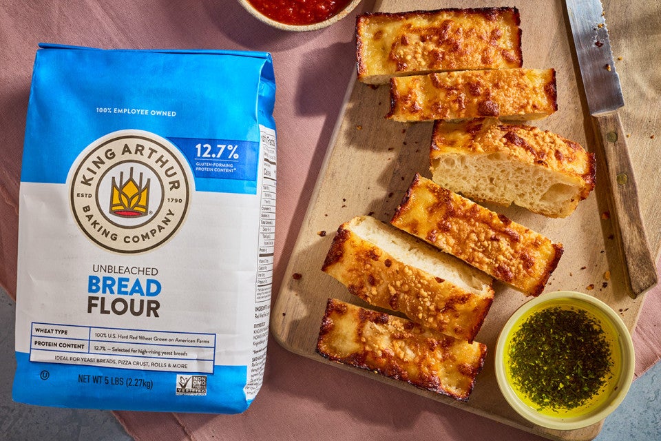 Small-Batch Cheesy Focaccia sliced on a cutting board with a bag of King Arthur Baking Bread Flour