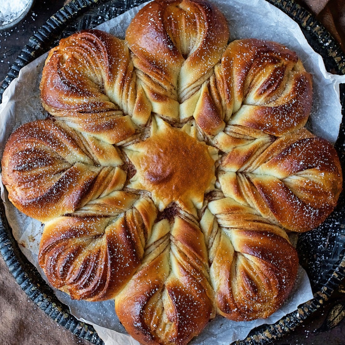 Braided and baked festive cinnamon star bread seen from above with a dusting of powdered sugar.