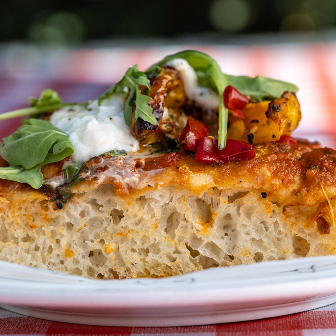 A side photograph of a slice of thick-crust pizza. - select to zoom
