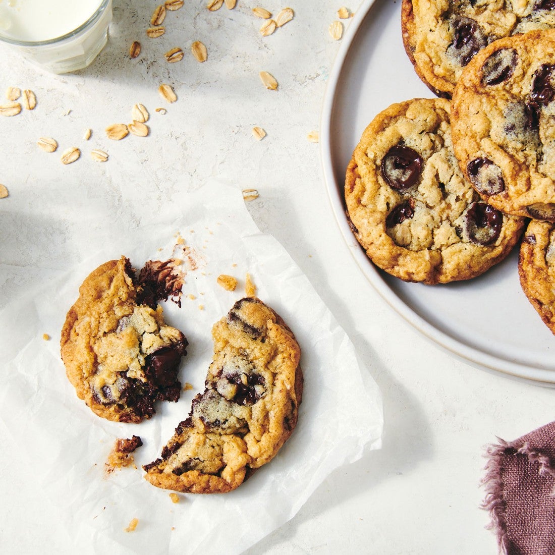 Looking down on a counter with chocolate chip cookies on a plate and another on a napkin.